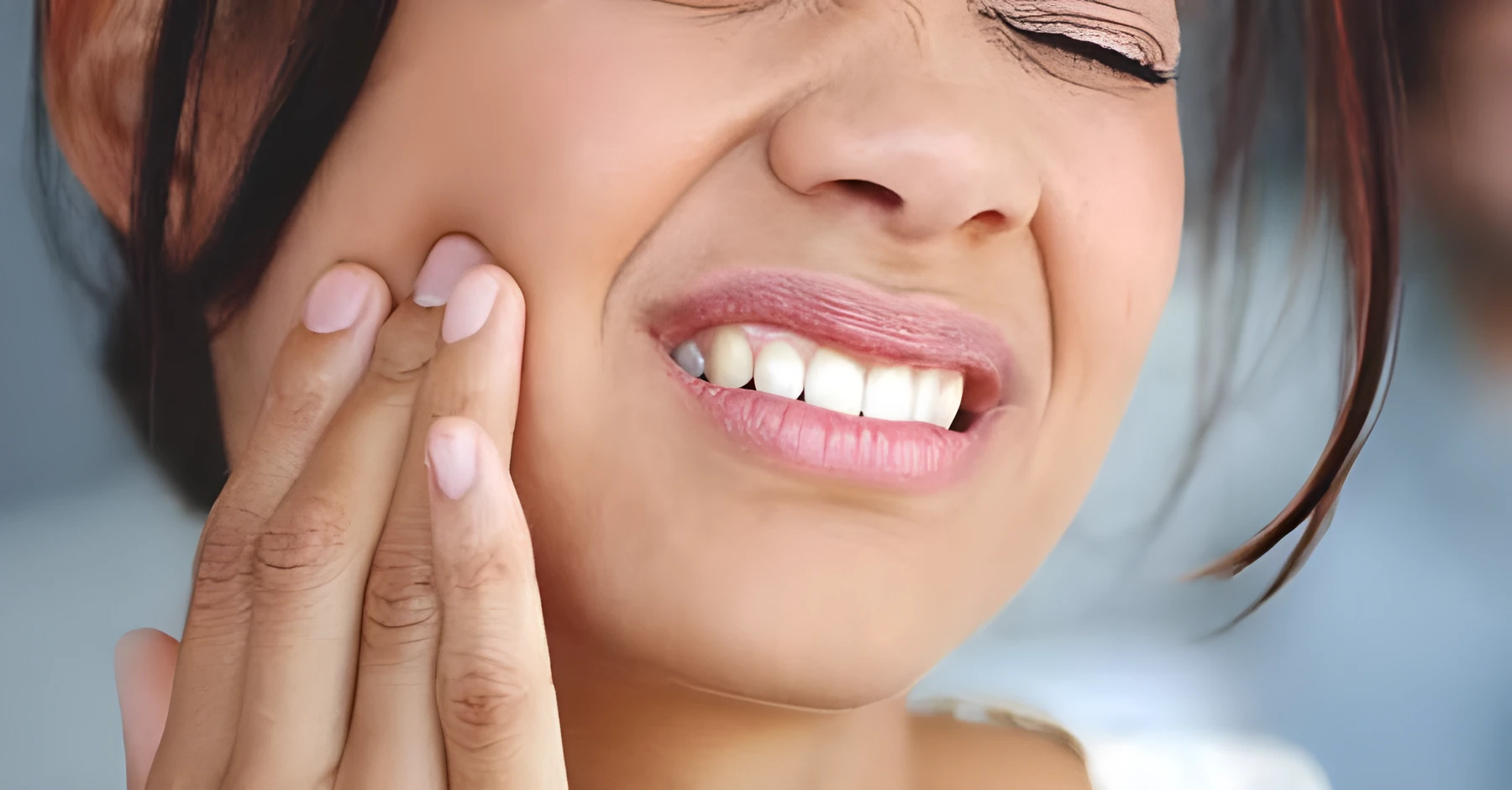 A woman holding her cheek in pain from a toothache