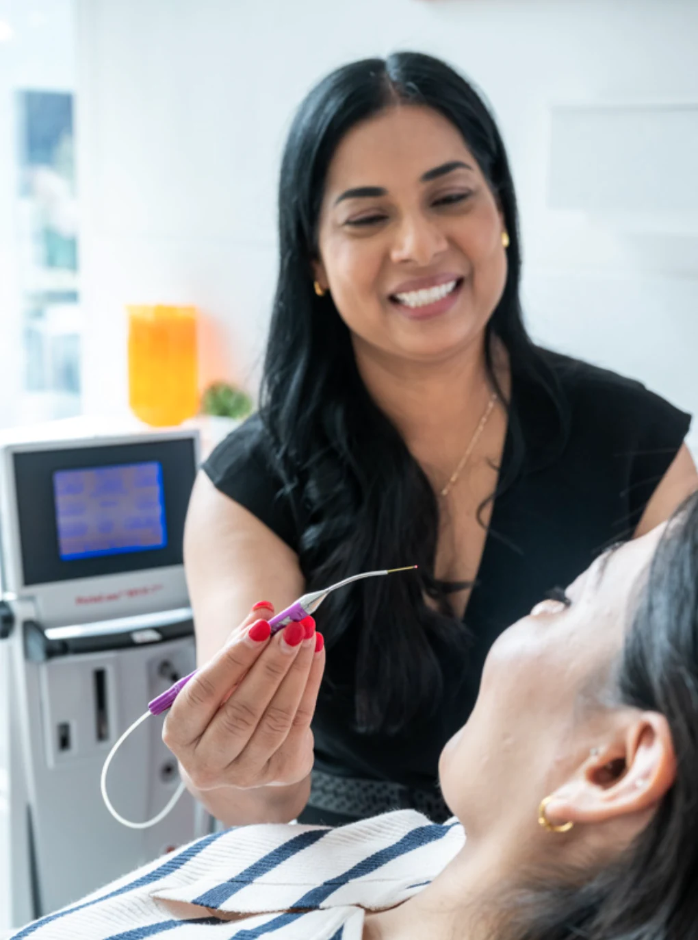 Dr Renu Karn holding the PerioLase laser handpiece beside a smiling patient
